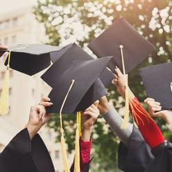 Graduation caps are held in the air by graduates.